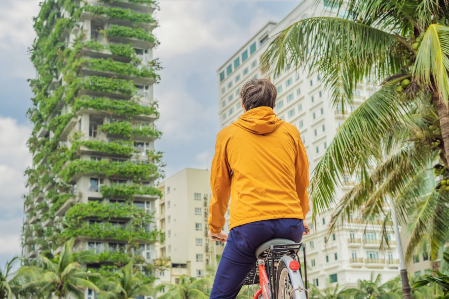 一名骑自行车的男子抬头看着一座覆有绿色植物的摩天大楼