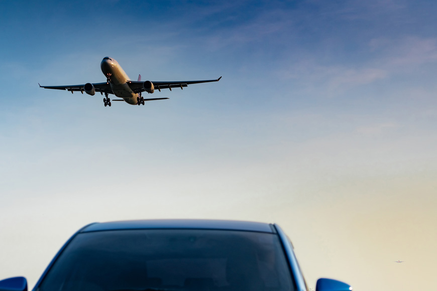一架飞机在机场停在机场的蓝色汽车的挡风玻璃上方