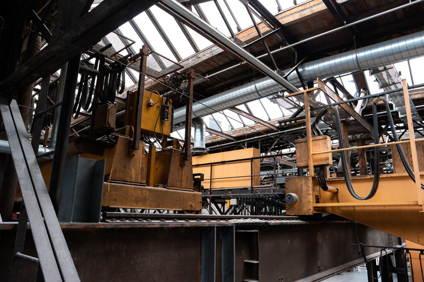 一台沉重的黄色机器位于一个废弃工厂的平台上，带有凸起的轨道。