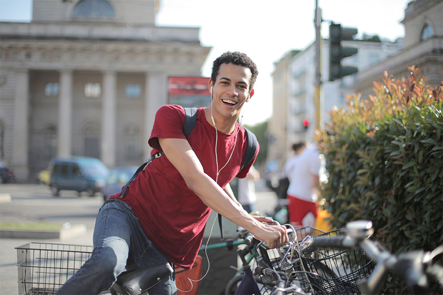 一个年轻的男性一边听着音乐一边高兴地骑着自行车准备停车