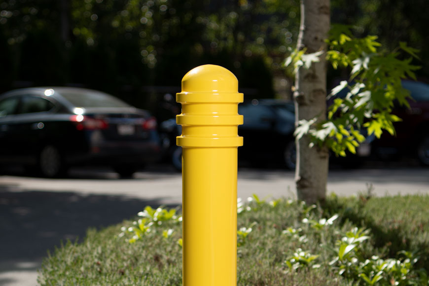 一个明亮的黄色系柱在装满汽车的停车场中高度可见