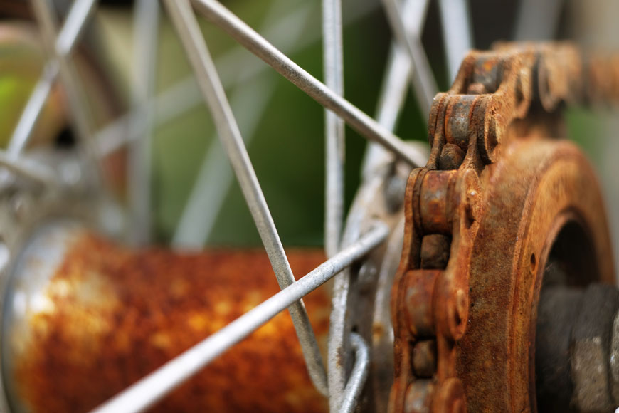 这张特写照片显示，自行车链条上布满了铁锈，车轮上布满了小锈斑