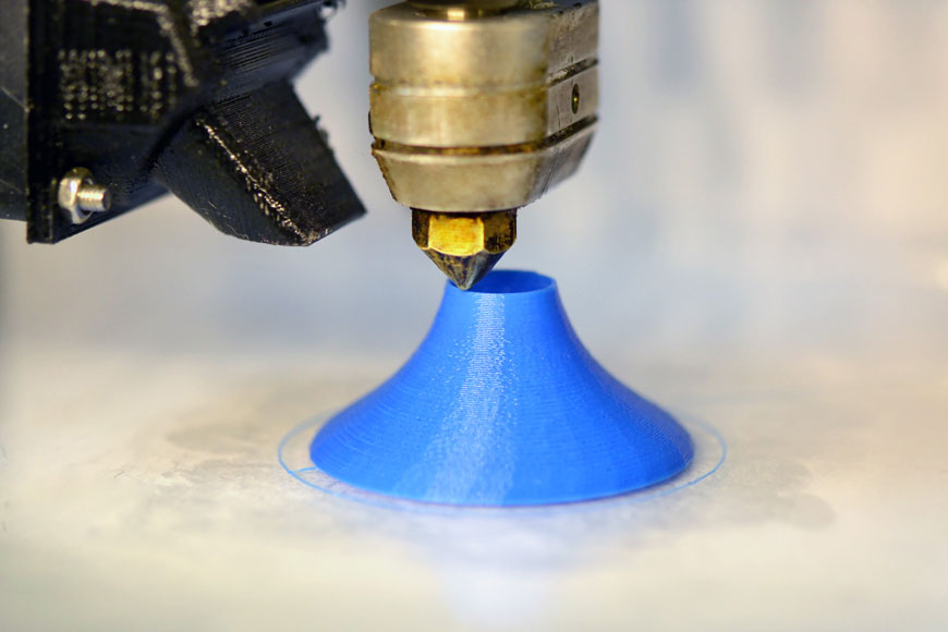 3D打印机挤出蓝色塑料并构建小物体的法兰底座