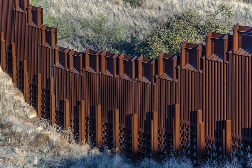 一个红色的钢栅栏坐落在亚利桑那州和墨西哥之间的边界上