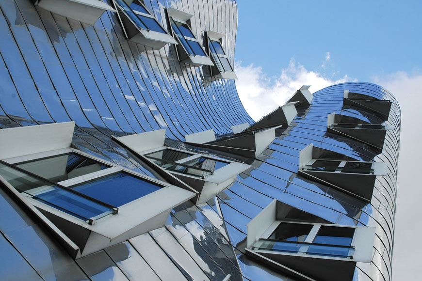 一栋不锈钢覆盖式现代主义建筑，弯曲的墙壁驶向蓝天。