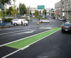 一个绿色彩绘的自行车箱坐在繁忙的十字路口之前，在高速公路上架上