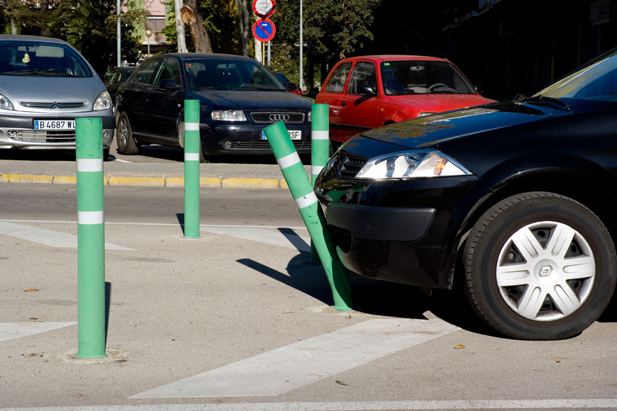 一个绿色的弯头柱子在黑色汽车的保险杠下弯曲