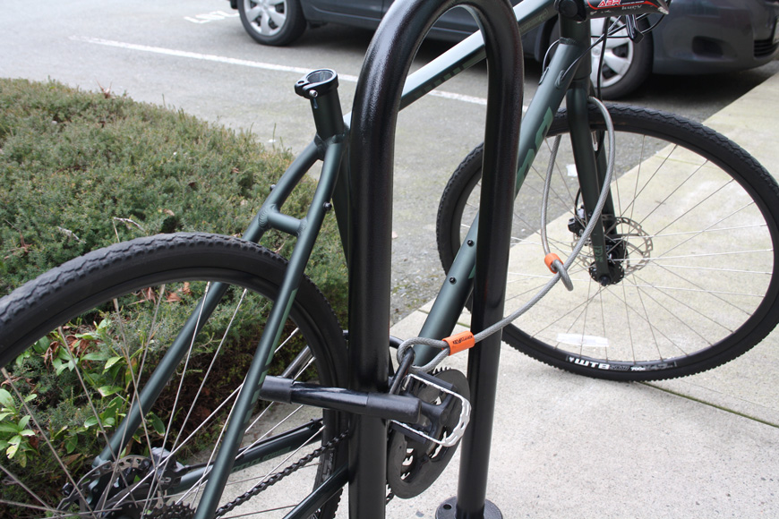 一辆锁在u形户外自行车架上的绿色自行车失去了座位
