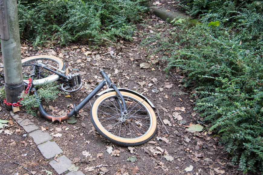 一辆被严重破坏的自行车被拴在路灯柱上。