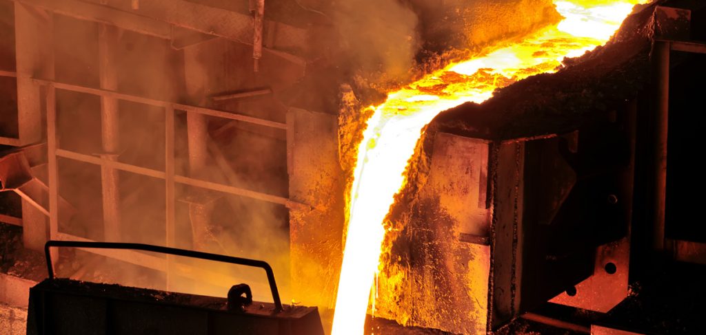 在铸造厂，热熔融钢从爆炸炉中流动，然后被铸成锭