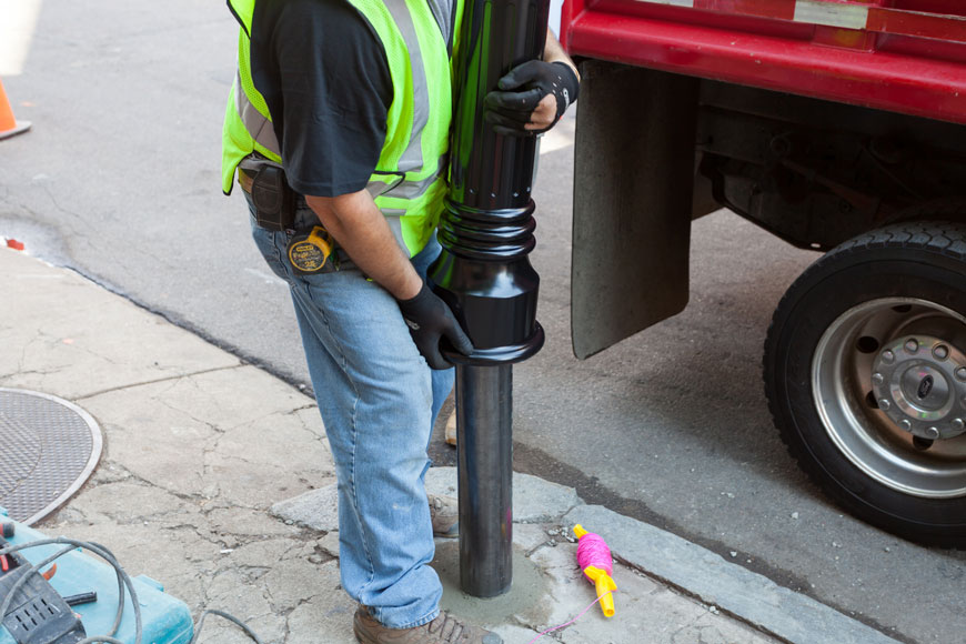一个工人在芬威公园的钢管柱布上设置了一个系螺栓盖。