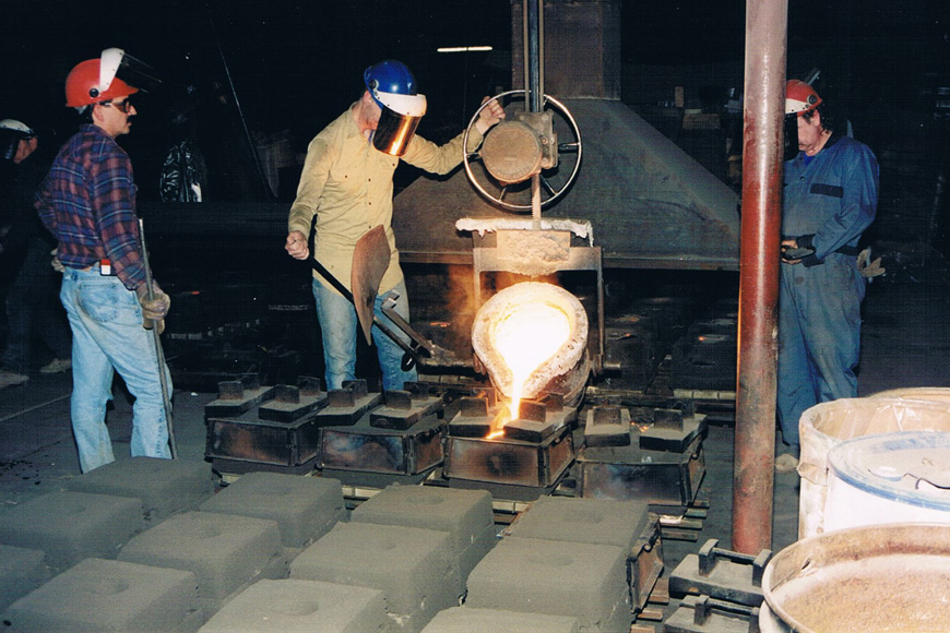 两位铸造工看另一堆钢注入一模 并加重闭合