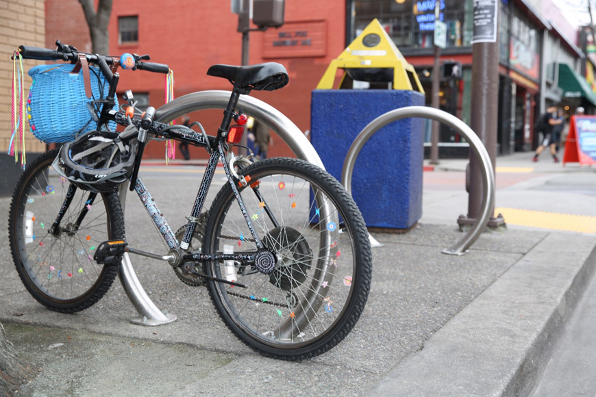 una bicicleta decorativaestáasegurada a cicloestacionamiento tanto con el Candado de cadada como como con el Candado en u