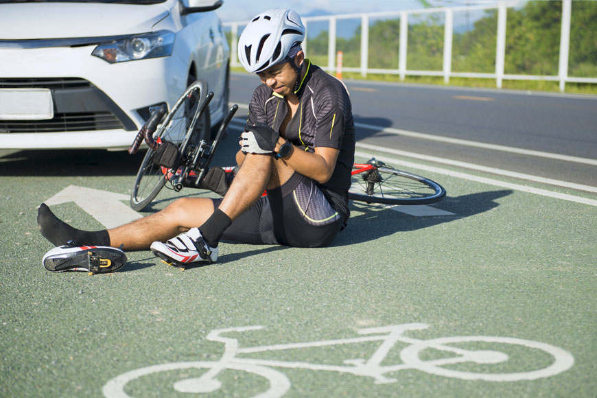 事故发生后，一名受伤的骑自行车的人坐在分离的自行车线上