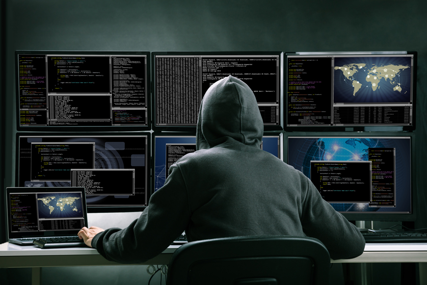 连帽衫的一个男人坐在电脑屏幕的前面