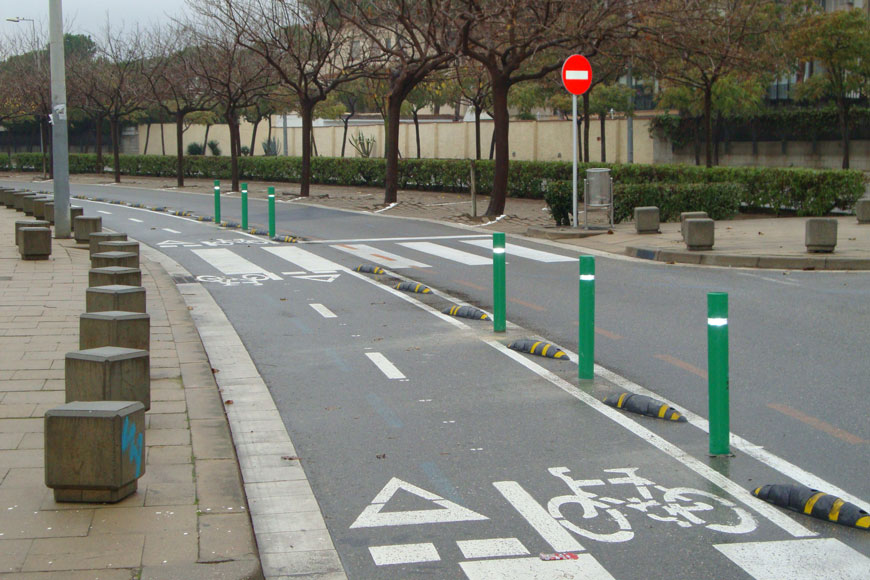 一排坚固的绿色弹性柱子保护着一条自行车道