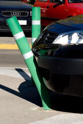 一根绿色的可弯曲的系柱在一辆黑色汽车的保险杠下弯曲