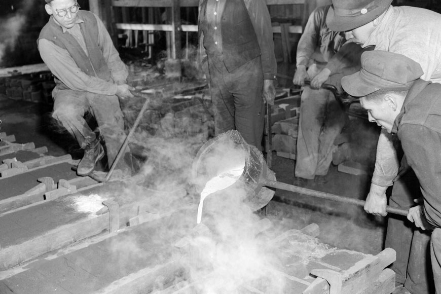 在一张老的黑白照片上，铸造工人把熔化的铁倒进砂型中