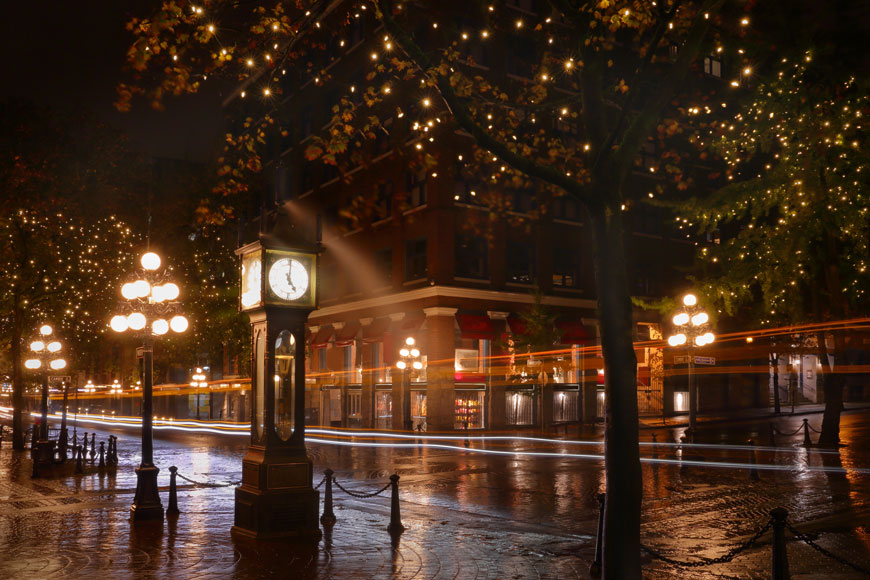 在历史悠久的市中心的一个漆黑的夜晚，球灯和蒸汽钟的灯光投射出金色的光芒。