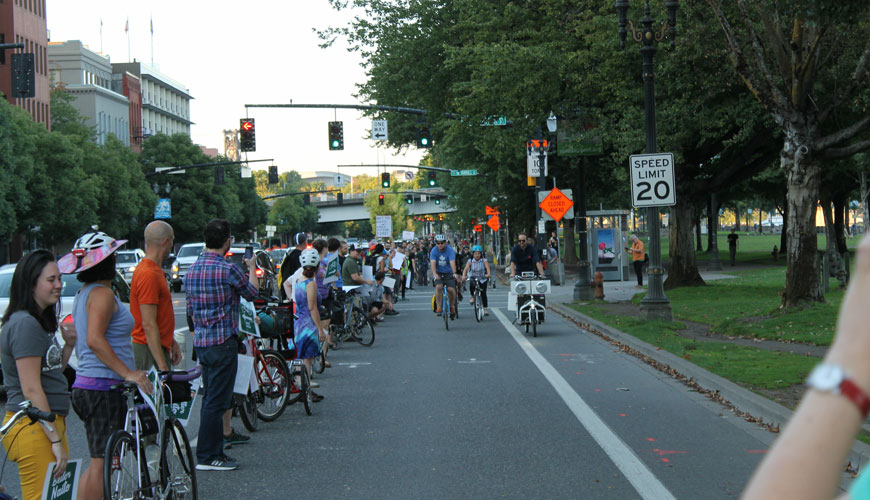 一行人站在自行车道和车流之间，为骑自行车的人加油