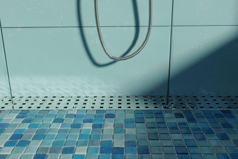 浴室的墙壁是蓝色的，地板是蓝色的马赛克瓷砖，还有一个带小方形孔的不锈钢格栅