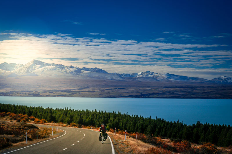 骑自行车的人在背景中爬上山丘，海洋和山脉