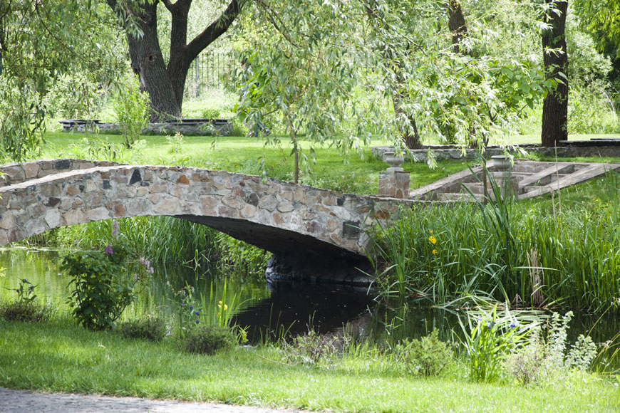 一座石桥横跨一片被柳树环绕的水域的田园风光