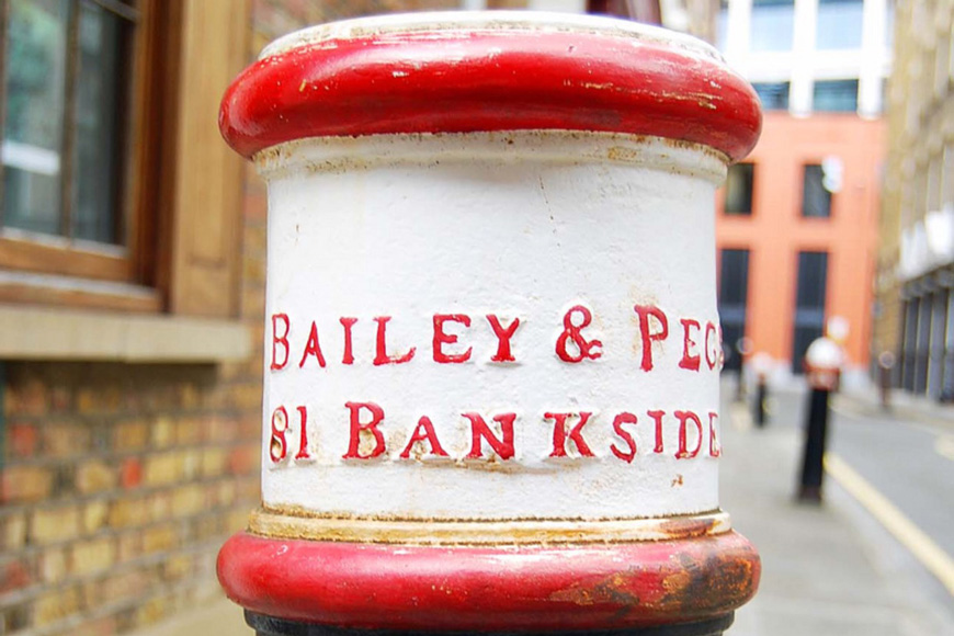 一个涂着黑、白、红三色的老式炮柱，上面是贝利与佩吉(Bailey & Pegg)街81号的浮雕