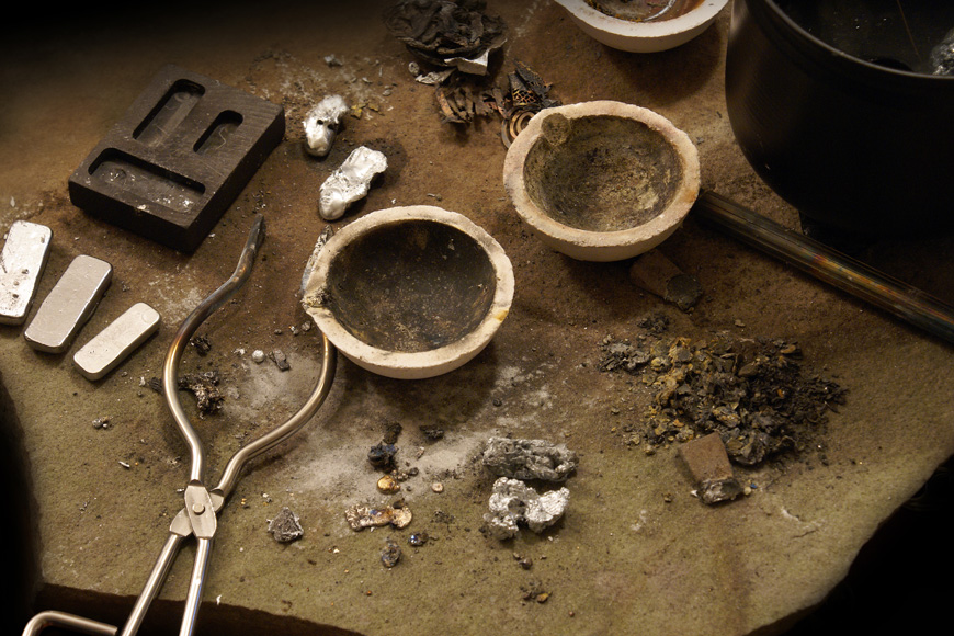 Metalúrgicono ferroso deja lingotes de plata y pepitas de oro al lado de callanas y moldes