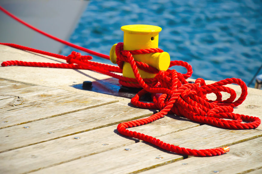 在波涛汹涌的海面上，一根短小的黄色系泊柱被鲜亮的红绳捆扎着