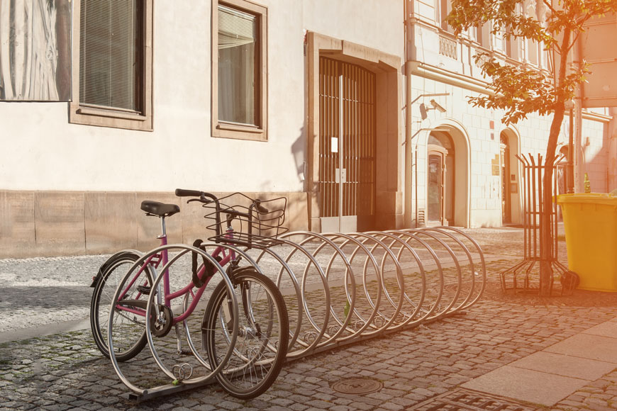 欧洲街的清晨：一辆粉红色自行车被锁定在螺旋银架上。