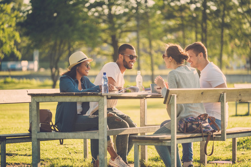 一群朋友坐在公园里的一张大野餐桌旁