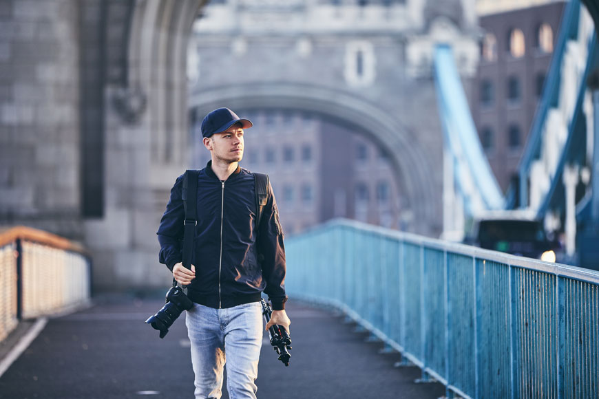 一位年轻的男性摄影师走过伦敦的塔桥