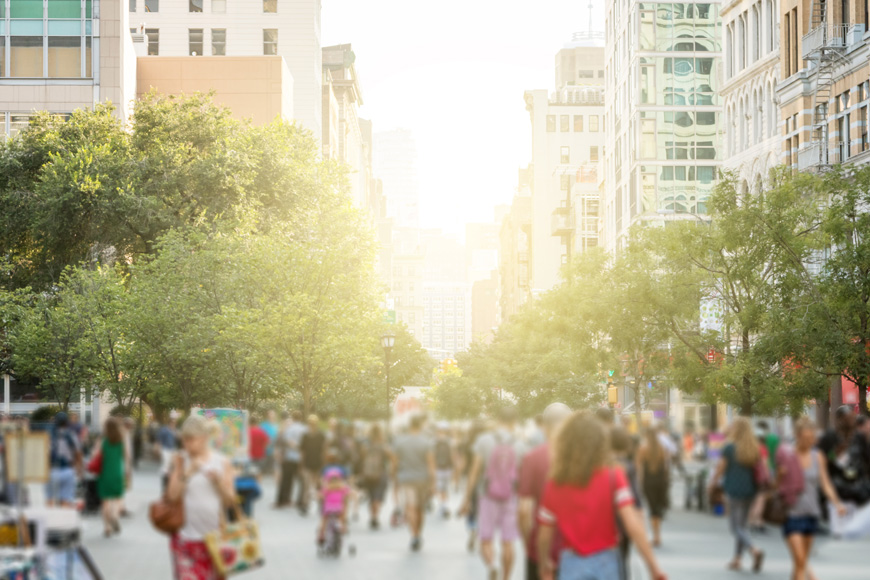 一张模糊的图像显示了曼哈顿一个繁忙的公园，阳光透过后面的建筑物照射进来。