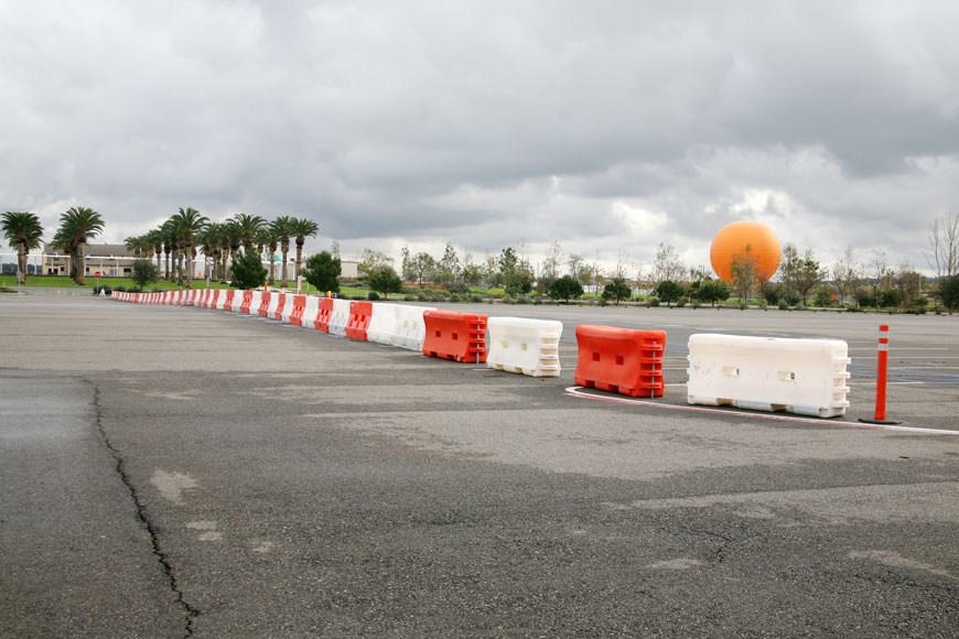 橙色和白色的塑料栅栏将一个被棕榈树环绕的停车场隔开