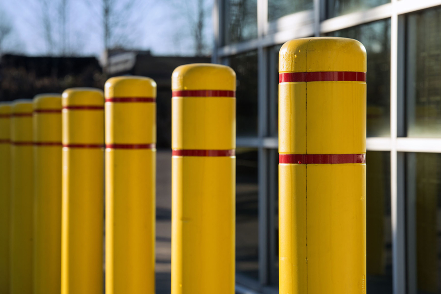 黄色的塑料护柱覆盖着红色的反光胶带排列在办公楼前