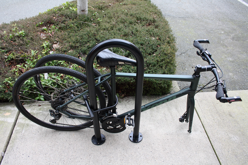 一辆绿色自行车的前轮胎被拆除，并与后轮胎锁在户外自行车架上
