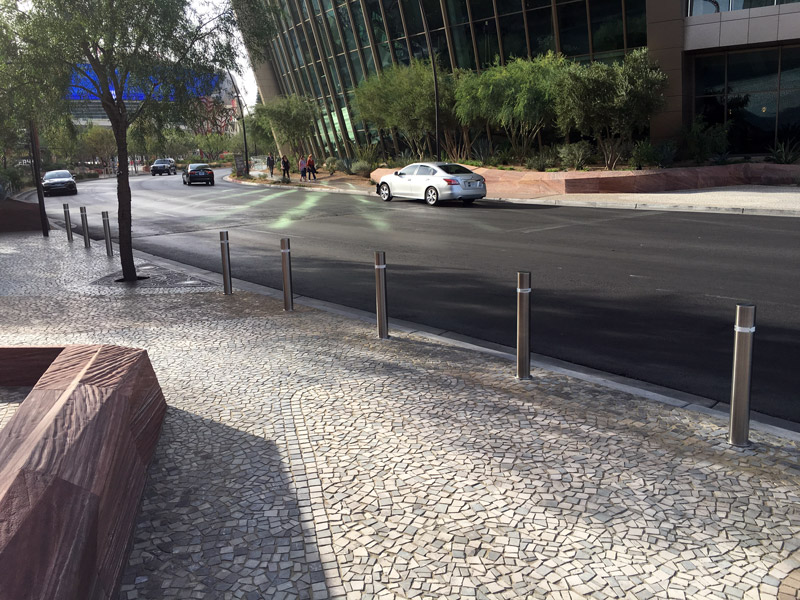 在拉斯维加斯的街道上，白色鹅卵石铺着一系列圆柱形的可伸缩不锈钢护柱