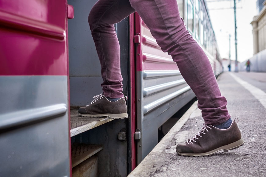 一名身穿紫色牛仔裤的男子爬上通勤列车的近距离镜头。