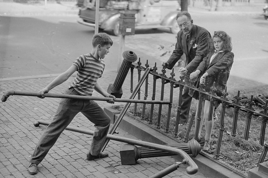 一个有大管子的男孩折断了一个老男人和一个女孩握着的篱笆。柱布和扶手位于地面上