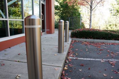 在人行道和停车场之间，有三个不锈钢护柱覆盖着反光胶带